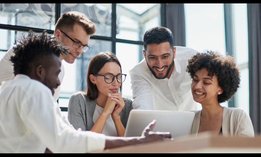 Happy team of workers looking at a computer.